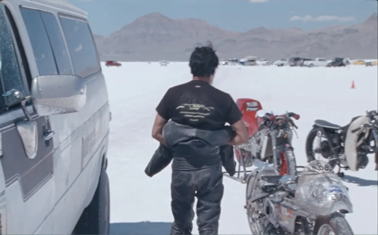 The Greasy Hands Preachers (2014) movie still: fullbody — A vast white salt flat landscape features distant hills under a clear blue sky. A man…