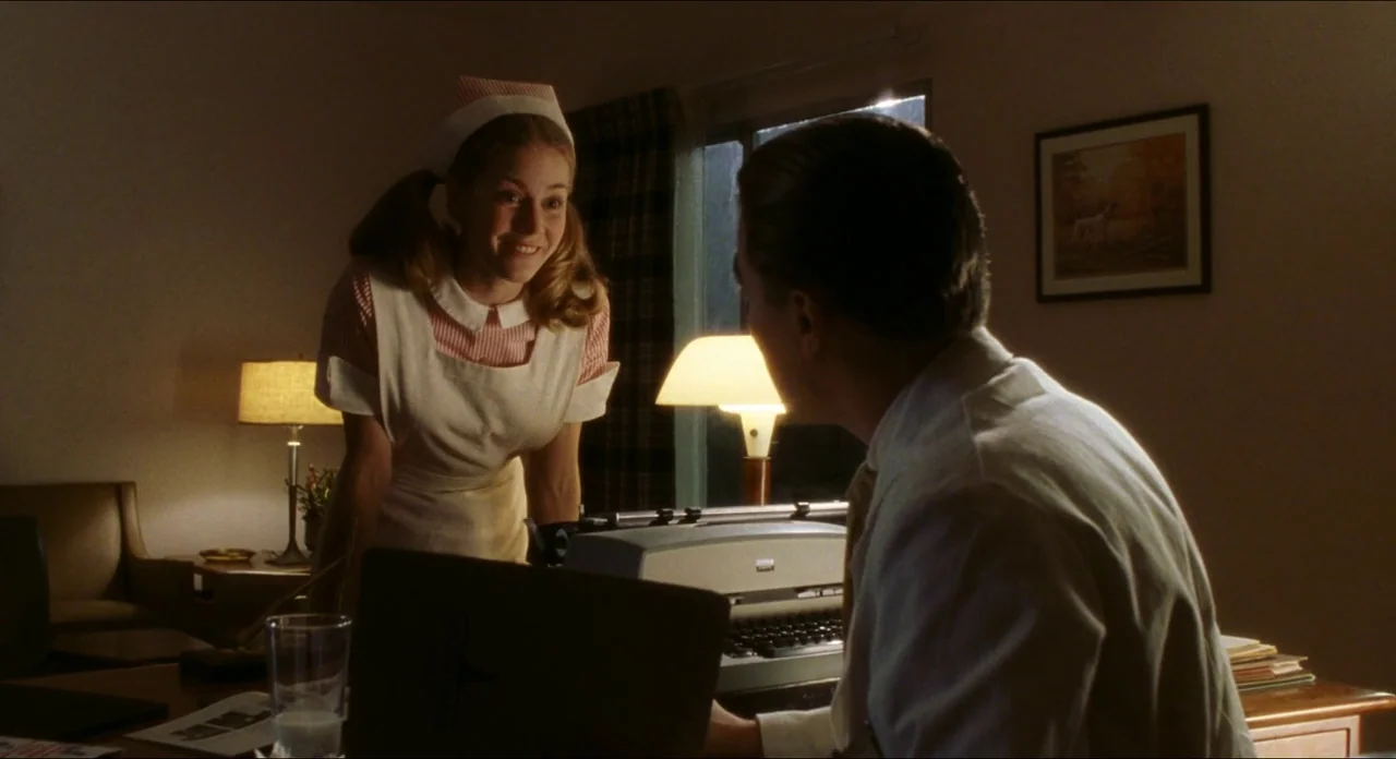 Catch Me If You Can (2002) movie still: medium — A dimly lit room with mid-century modern furniture and a desk holding a typewriter. A nurse stands…