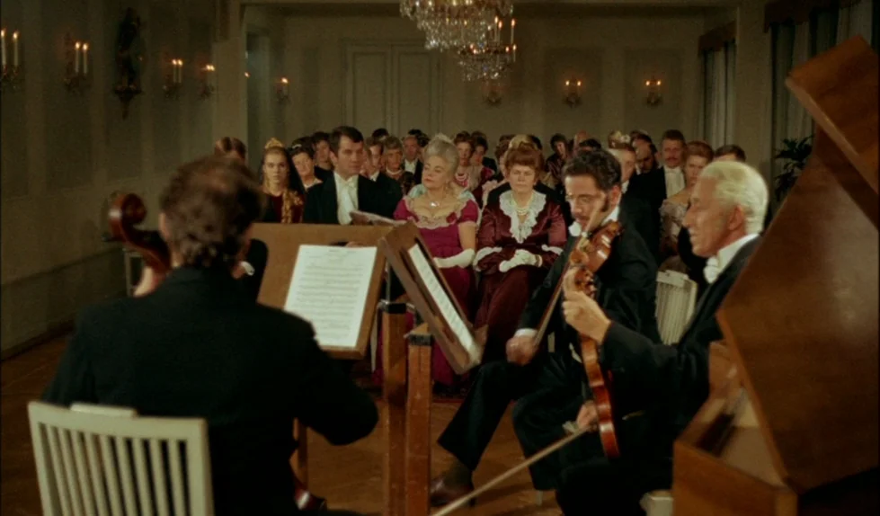 Elvira Madigan (1967) movie still: wide — A formal interior with parquet floors and crystal chandeliers hosts an audience. Three musicians in…