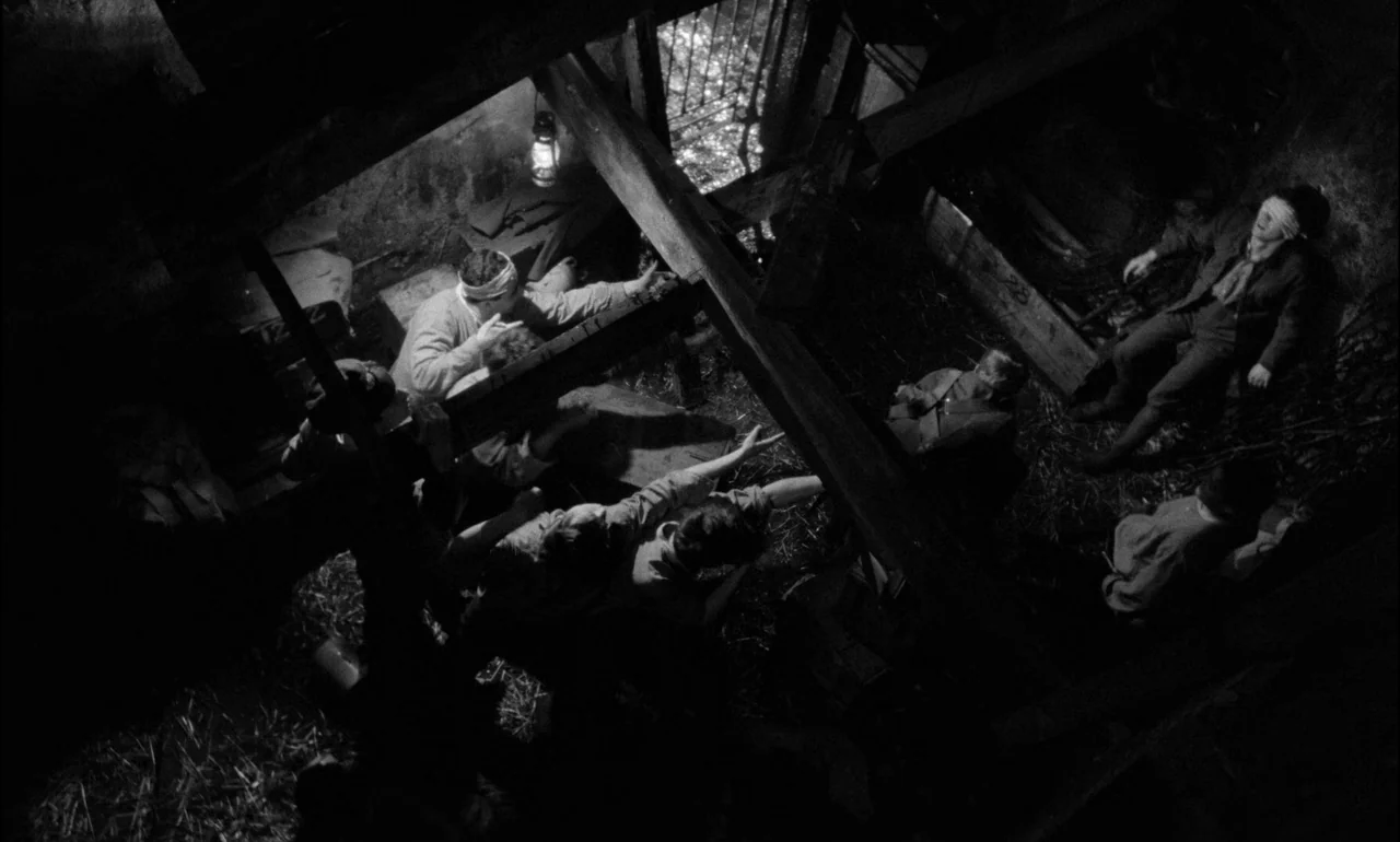 King & Country (1964) movie still: wide — A rustic barn interior features wooden beams, straw bedding, and dark, shadowed corners. Multiple…