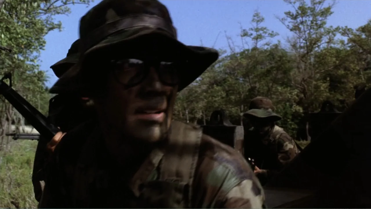 Heartbreak Ridge (1986) movie still: medium — A dense outdoor location with trees and foliage surrounding a group of soldiers. A soldier in…