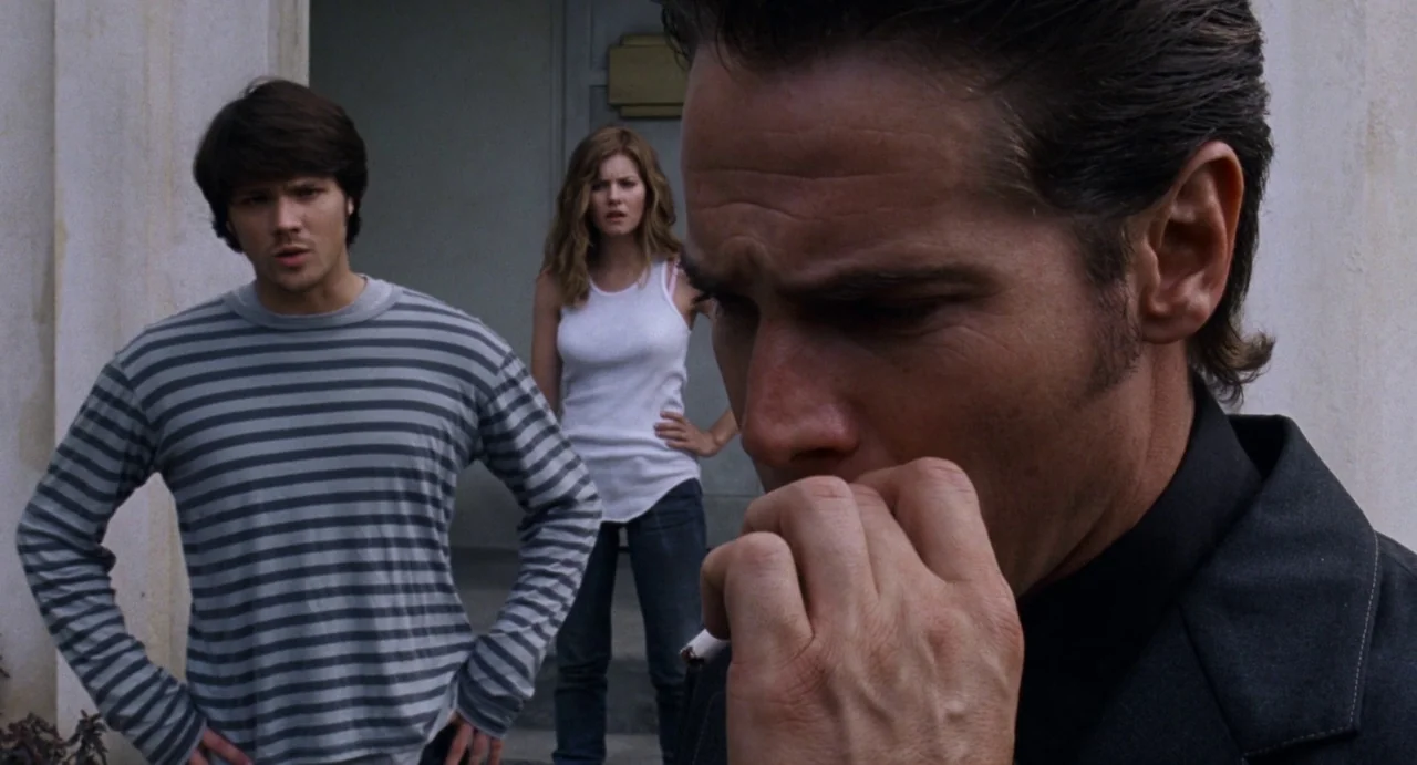 House of Wax (2005) movie still: medium — A residential porch with a concrete wall background during the daytime. A man in the foreground smokes…