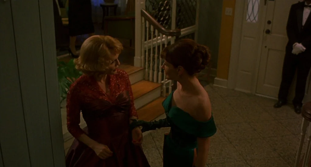Far From Heaven (2002) movie still: medium — A classic residential foyer features a wooden staircase and a white-paneled entry door. Two women in…
