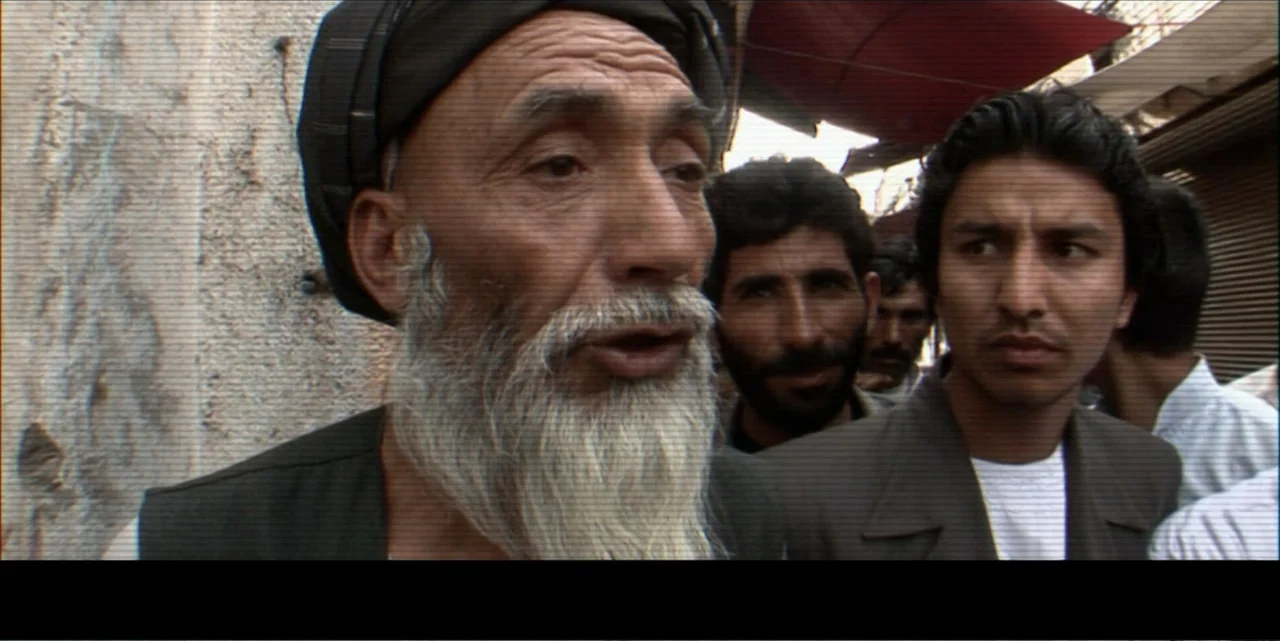 Silencing the Song: An Afghan Fallen Star (2011) movie still: closeup — An outdoor market environment features people standing in close proximity…