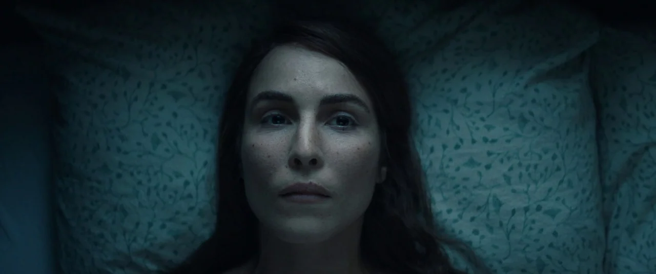 Babel (2006) movie still: closeup — A bedroom at night with a person lying on a patterned bed pillow. The woman is centered in the frame, looking…