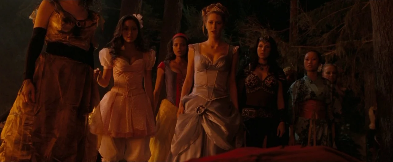 Trick ‘R Treat (2007) movie still: fullbody — A group of women in varied fantasy costumes stand together in a dark forest at night. They appear to…