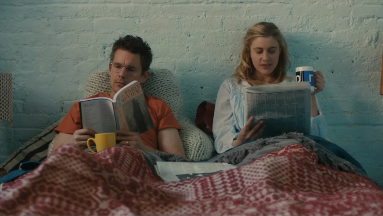 Maggie's Plan (2016) movie still: medium — A modern bedroom features a light blue brick wall behind a bed with patterned blankets. A man and a woman…