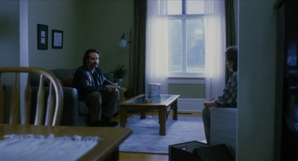Narc (2002) movie still: wide — A green-walled room features two couches flanking a wooden coffee table near a window. A man in a leather jacket…