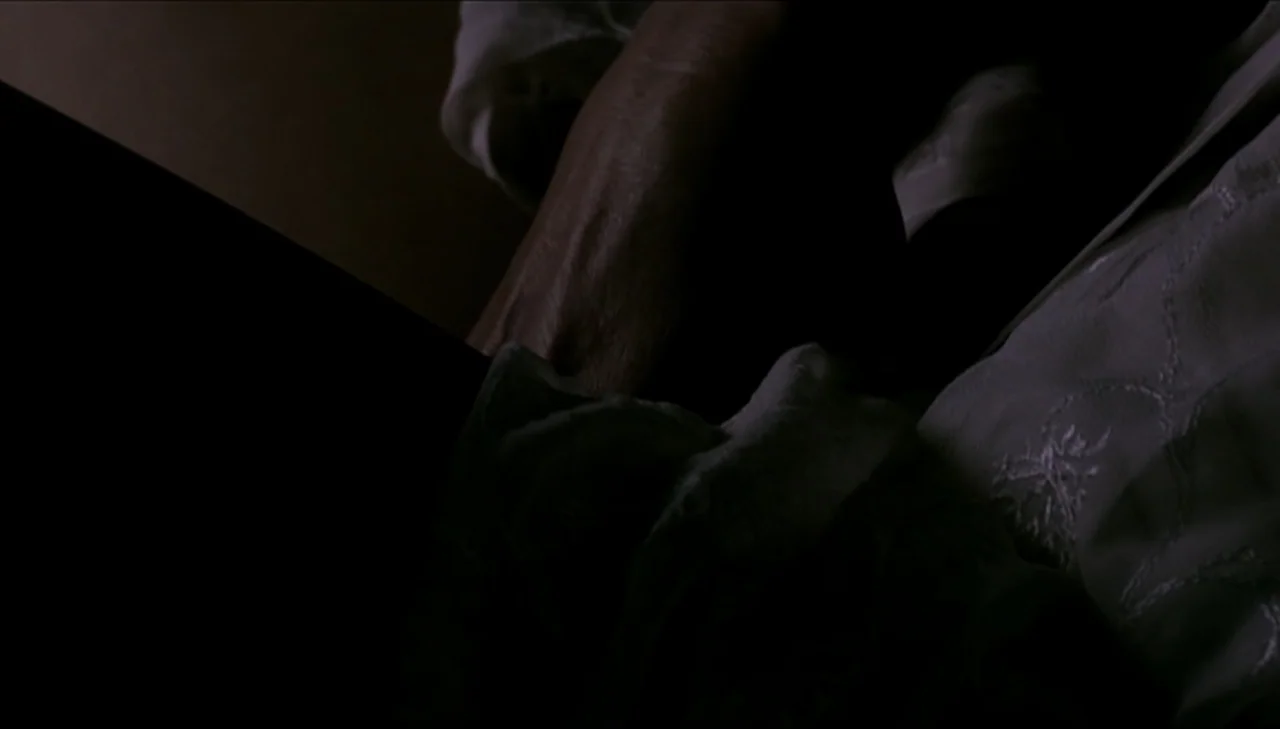 Dark Country (2009) movie still: closeup — A dimly lit interior space features white embroidered fabric lying on a dark surface. The textile shows…
