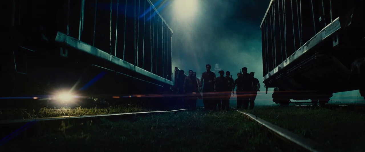 Making of: West Side Story (2021) movie still: wide — A dark, industrial railway yard at night features towering metal train cars on either side. A…