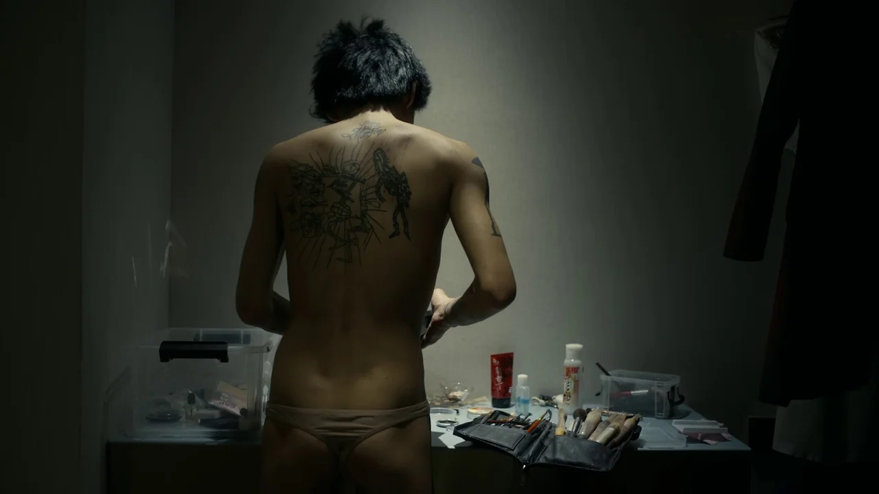 The Last Year of Darkness (2023) movie still: medium — A dimly lit room contains a white table cluttered with makeup brushes and bottles. An…