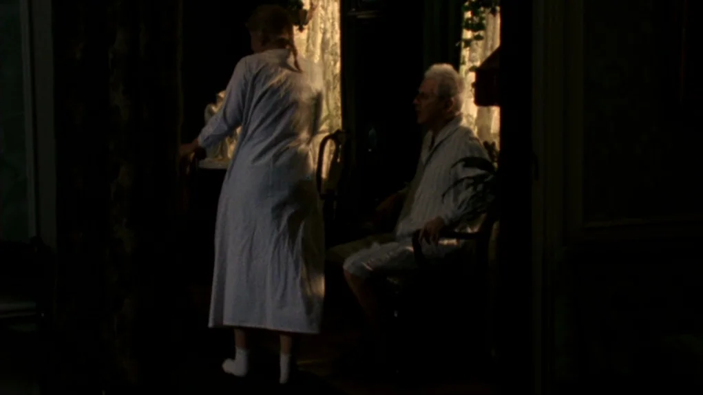 Face to Face (1976) movie still: medium — A dimly lit room with patterned curtains and furniture silhouettes against a dark backdrop. A woman in a…