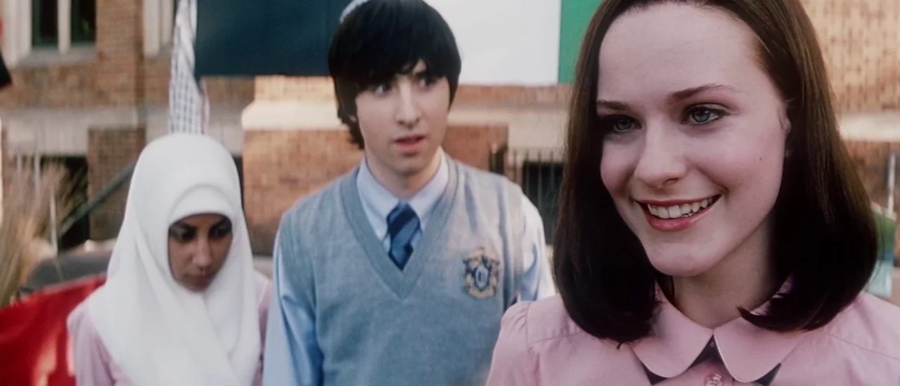 Pretty Persuasion (2005) movie still: medium — An outdoor area with a brick building in the background featuring a flag. Three students stand…