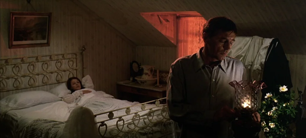 Ryan’s Daughter (1970) movie still: medium — An attic room with sloped ceilings contains a metal-frame bed and a small table. A man stands holding a…