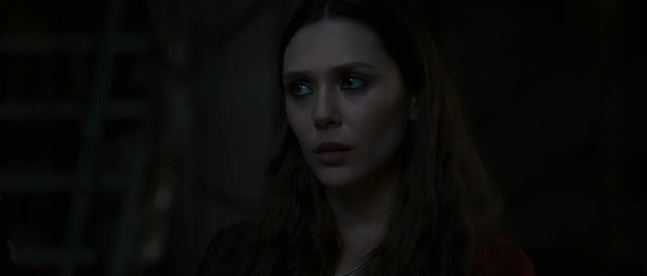 Avengers: Age of Ultron (2015) movie still: closeup — A woman stands in a pitch-black space with no visible background details. She looks to the…