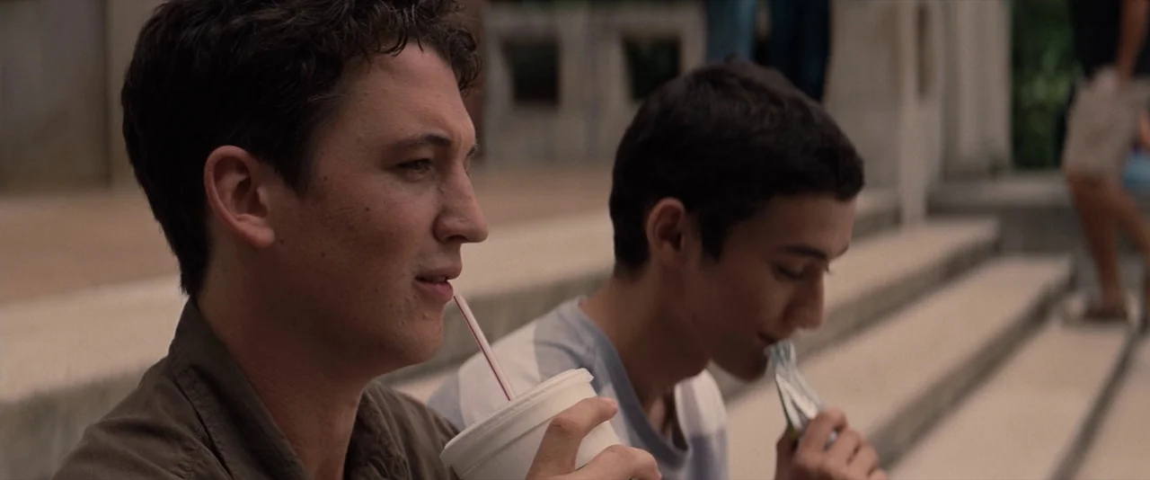 The Spectacular Now (2013) movie still: medium — Two men sit on wide concrete stairs outdoors during the daytime. One man holds a drink while the…