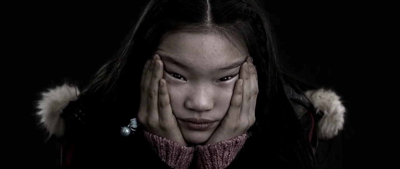 Lady Vengeance (2005) movie still: closeup — A young East Asian girl is shown in a tight close-up against darkness. She rests her face in both hands…