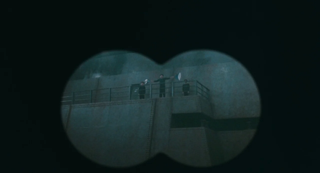 And The Ship Sails On (1983) movie still: wide — A high, reinforced concrete wall rises steeply behind a metal railed walkway. Three small figures…