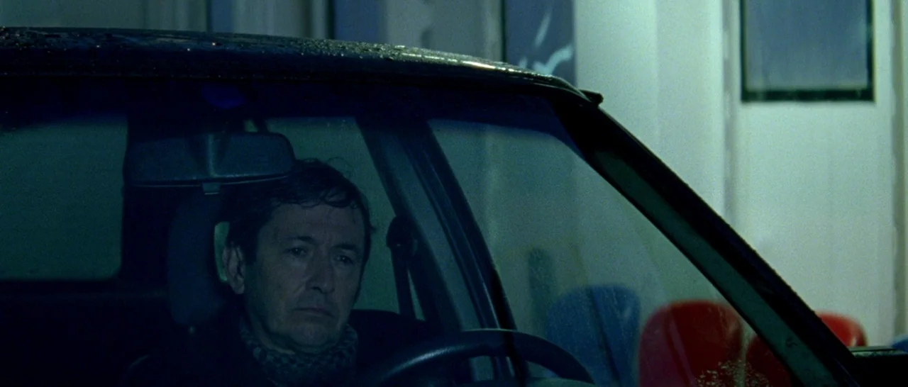 Arabian Nights: Volume 1 – The Restless One (2015) movie still: medium — A man sits inside a dark vehicle at night with damp glass. The environment…