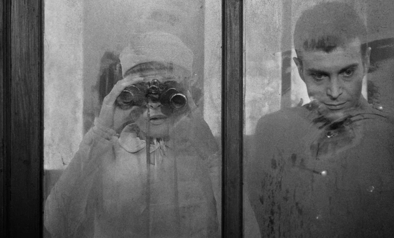 Goto, Island of Love (1969) movie still: medium — Two individuals stand behind a window pane showing signs of surface smudges and age. The woman…