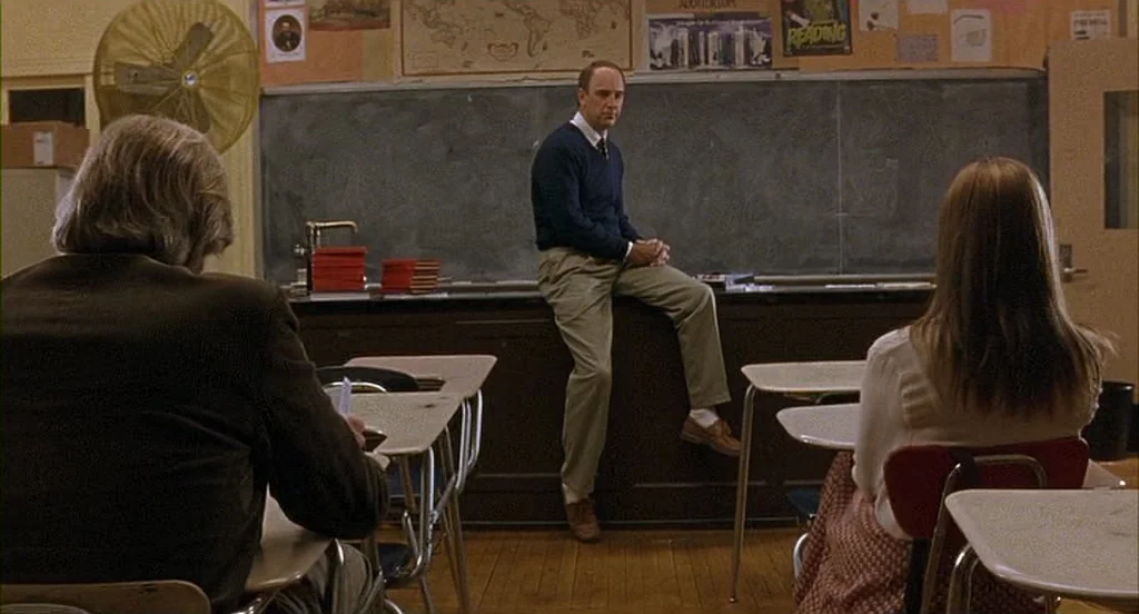 The Squid and the Whale (2005) movie still: medium — A high school room features a chalkboard covered with maps and posters. A teacher sits on his…
