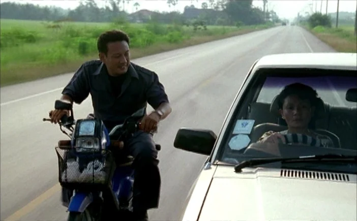 Blissfully Yours (2002) movie still: medium — A paved rural road stretches into the distance through green agricultural fields. A man on a moped…