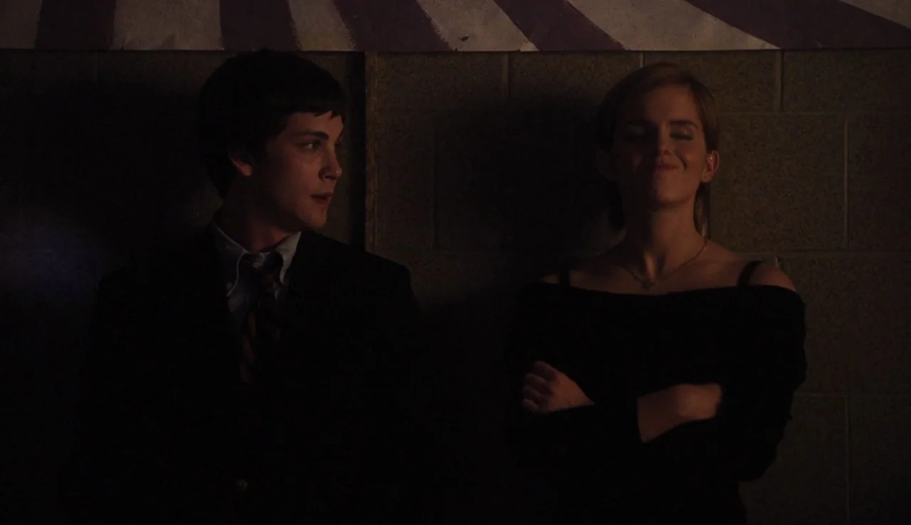 The Perks of Being A Wallflower (2012) movie still: medium — Two teenagers stand against a dimly lit concrete block wall with a painted graphic…