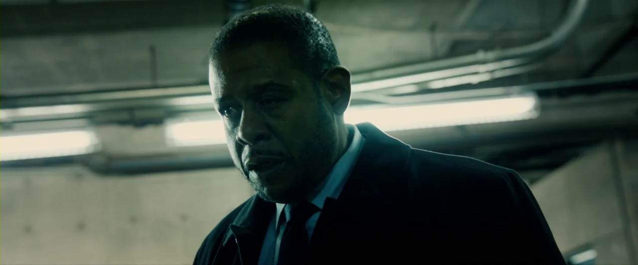 The Last Stand (2013) movie still: closeup — A dimly lit concrete parking garage with visible overhead utility piping and fluorescent lighting. A…