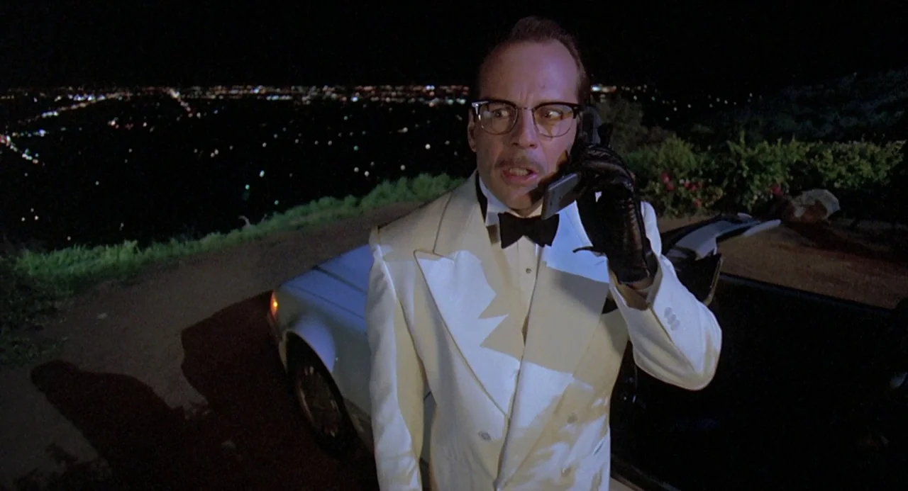Death Becomes Her (1992) movie still: medium — An overlook at night with city lights visible in the distance behind a man. A man in a white tuxedo…