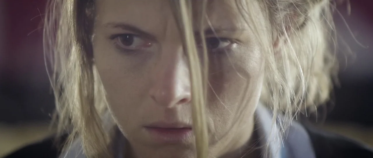Upstream Color (2013) movie still: closeup — A close-up shot focuses on a woman's face within an indoor environment. The subject stares intently…