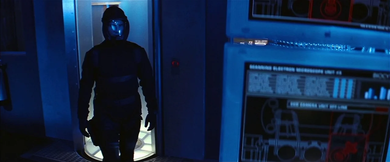 Mission: Impossible II (2000) movie still: medium — A dark laboratory interior features illuminated digital computer screens and metallic grated…