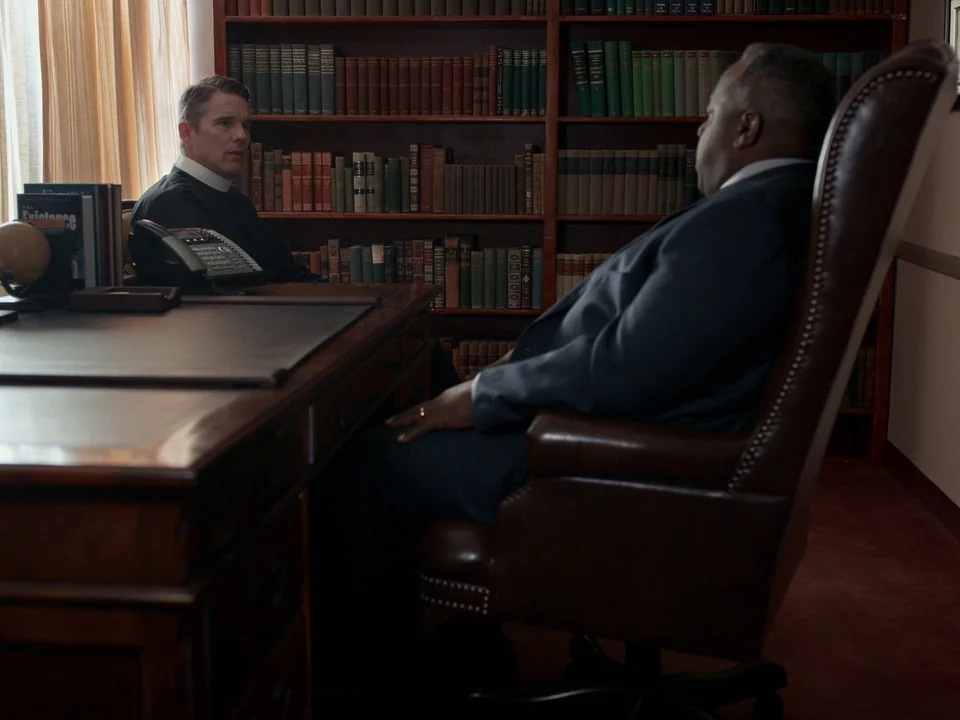 First Reformed (2017) movie still: medium — A wood-paneled room is filled with shelves of books lining the walls. Two men sit in chairs facing each…