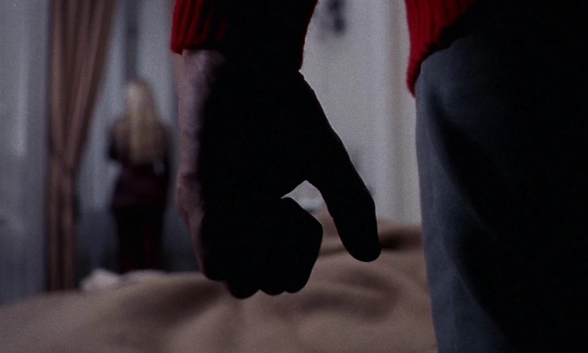 Daughters of Darkness (1971) movie still: closeup — A bedroom contains a man standing in the foreground with a clenched fist. In the blurred…