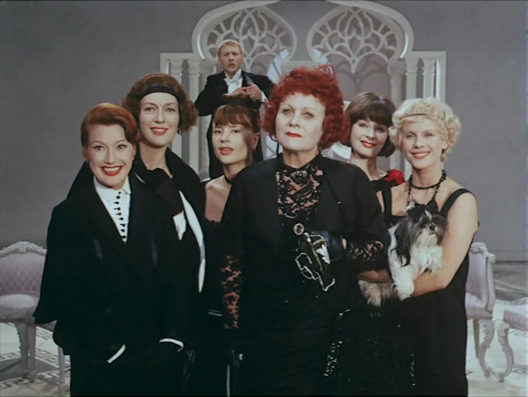All These Women (1964) movie still: medium — A group of formally dressed individuals stands in front of a decorative arched screen. The figures pose…
