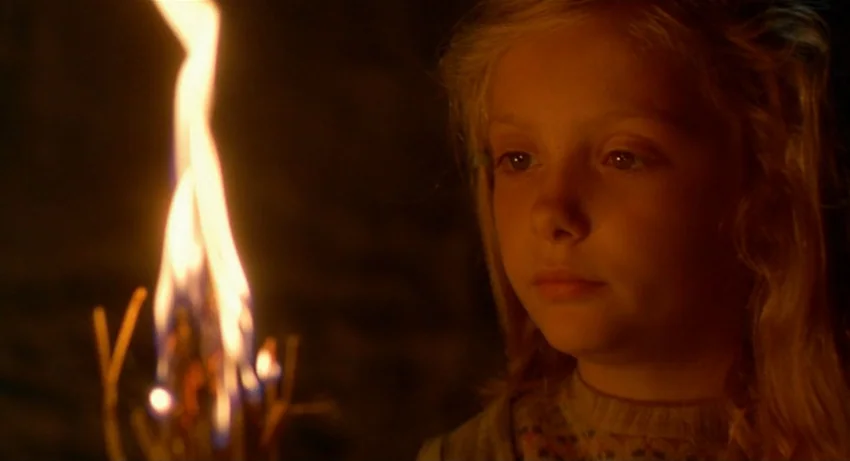 The Secret Of Roan Inish (1994) movie still: closeup — A dark, unlit room serves as the backdrop for a close-up of a girl. She looks toward a small,…