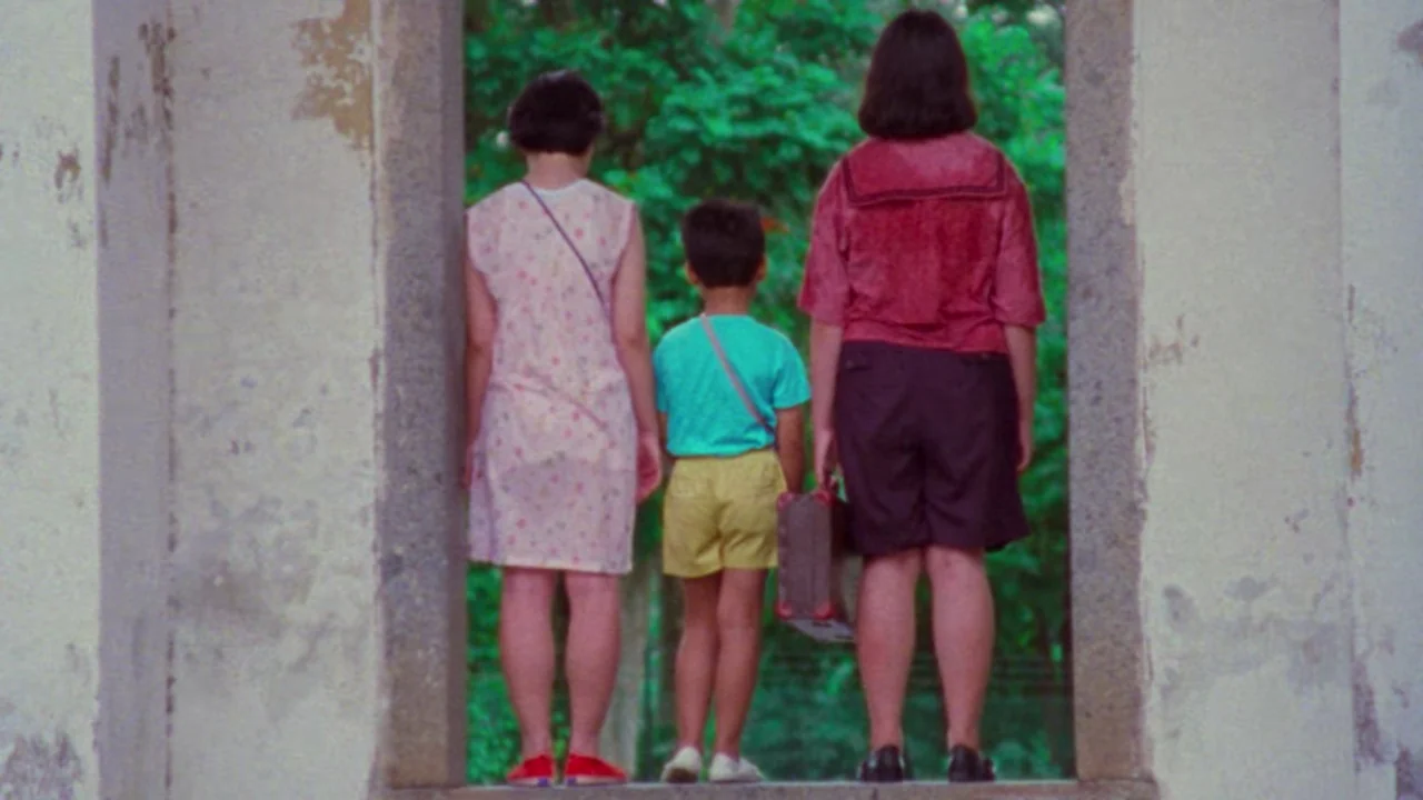 Shirkers (2018) movie still: fullbody — Three children stand in a weathered concrete stone archway facing out into trees. They are viewed from…