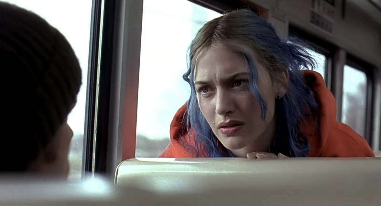 Eternal Sunshine of the Spotless Mind (2004) movie still: medium — The interior of a commuter train car with pale seats and large windows. A woman…