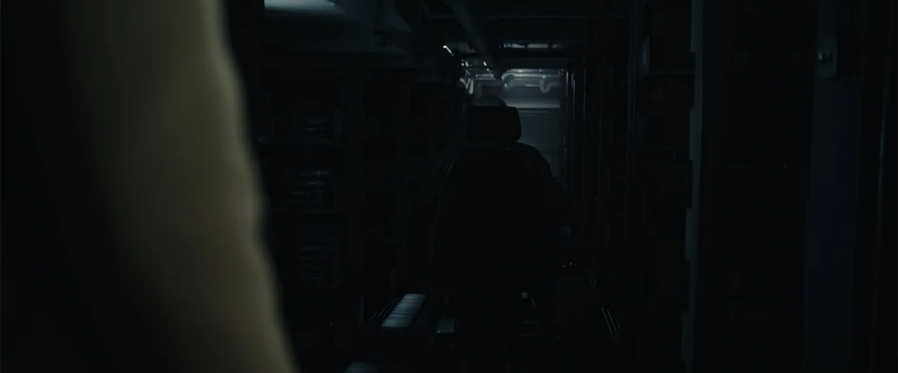 Moonfall (2022) movie still: medium — A dark industrial archive room features narrow aisles filled with tall metal shelving units. A solitary figure…