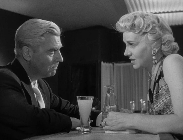 Bob le Flambeur (1956) movie still: medium — A dimly lit lounge with a counter and minimalist modern decor. A man and a woman face each other while…