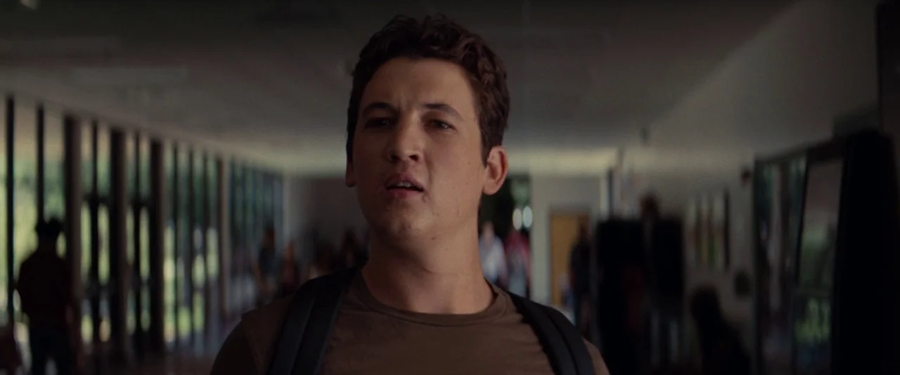 The Spectacular Now (2013) movie still: medium — A long educational facility corridor features floor-to-ceiling glass panels on one side. A young…