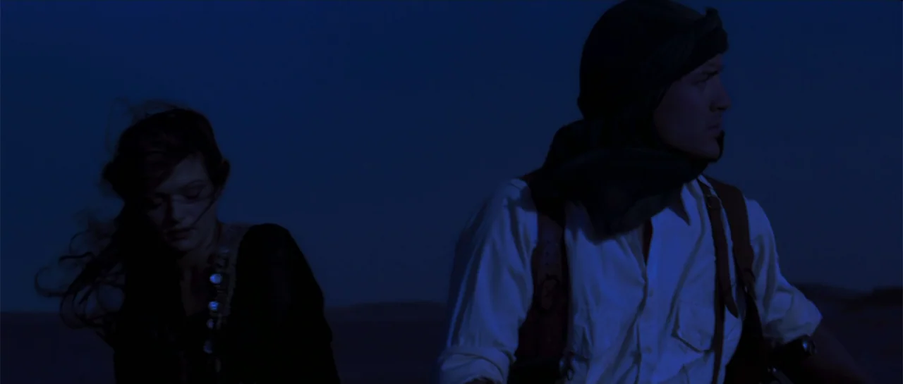 The Mummy (1999) movie still: medium — A dark, featureless desert landscape at night is illuminated by deep blue light. A man and a woman stand…