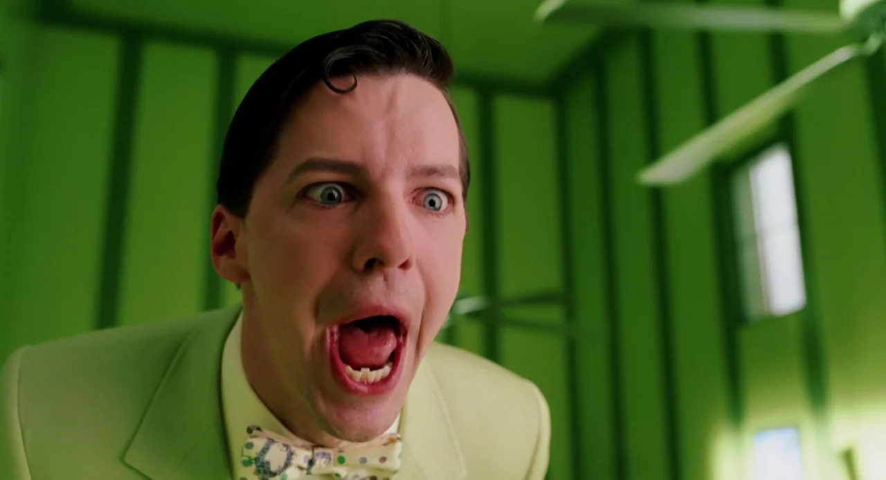 The Cat In The Hat (2003) movie still: closeup — A man in a green suit stands in a bright room painted in vibrant green. The man looks forward with…