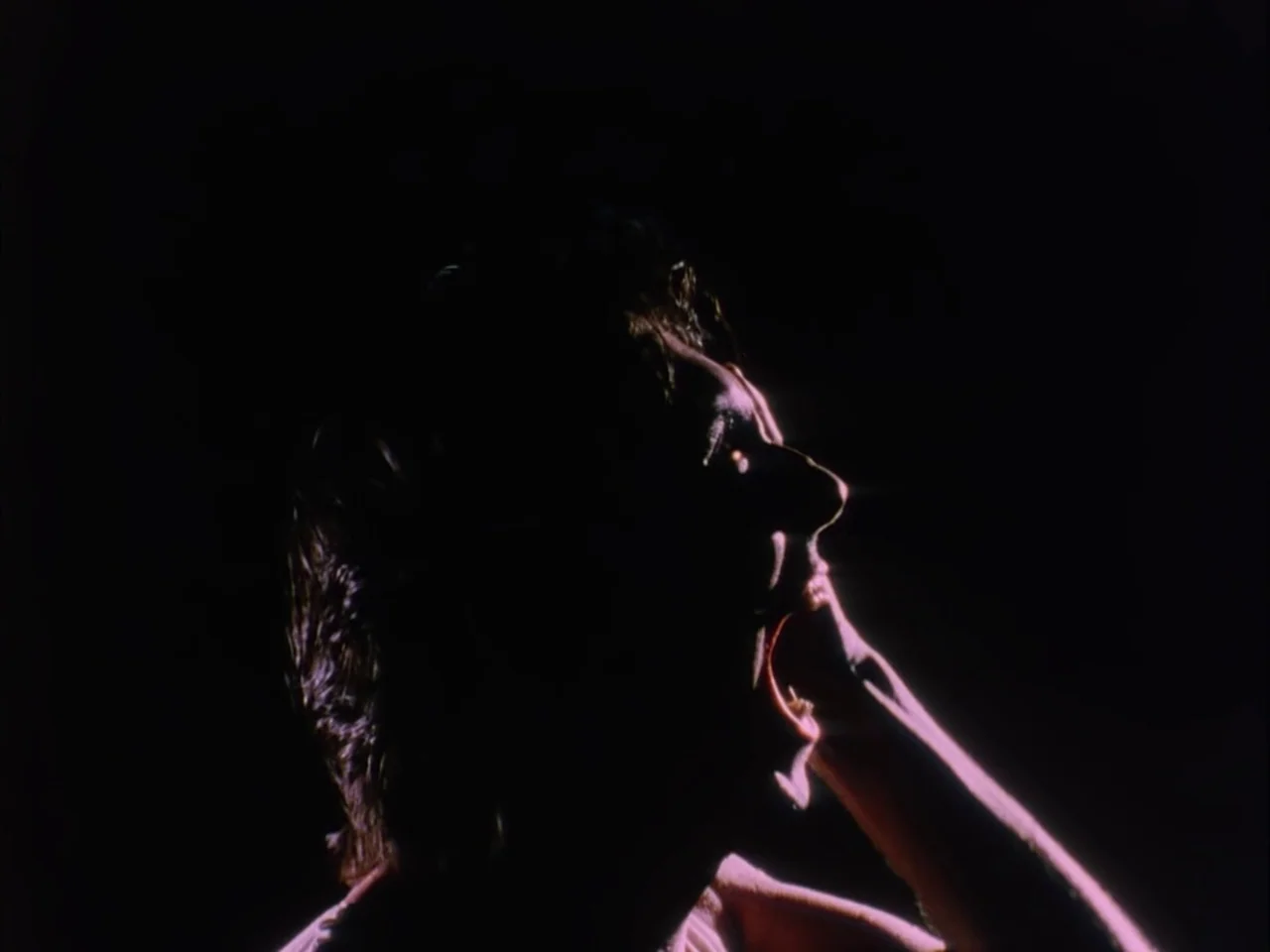 Subconscious Cruelty (2000) movie still: closeup — A dark, featureless environment serves as a background for a single figure. A person with dark…