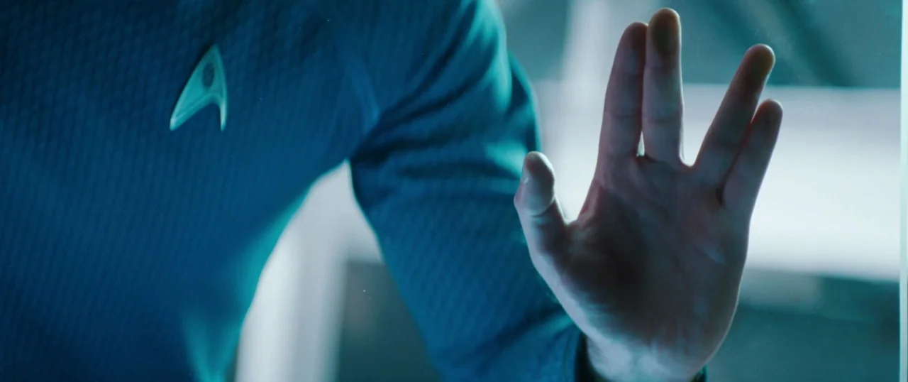 Star Trek Into Darkness (2013) movie still: closeup — A close-up of a person in a blue Starfleet uniform pressing their hand against glass. The…