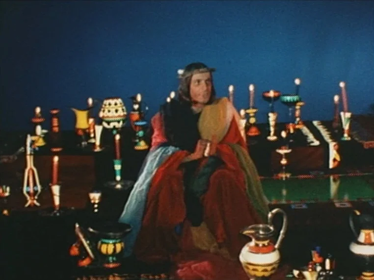Salome (1972) movie still: medium — A dimly lit chamber contains many small candles and various ornate, colorful clay vessels. A man in archaic…