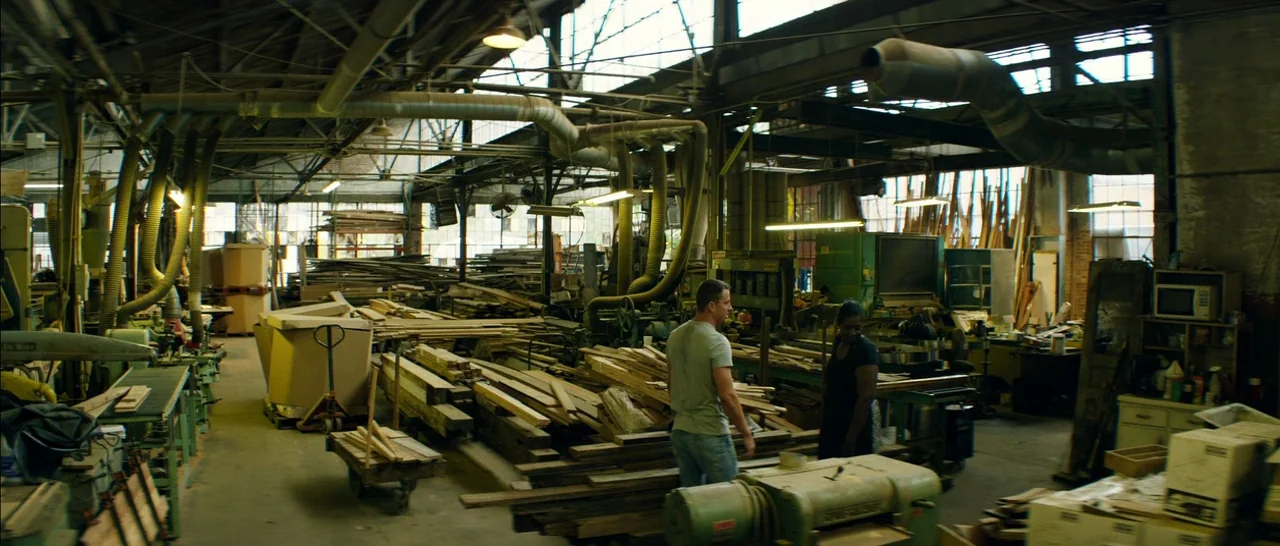 Magic Mike XXL (2015) movie still: wide — An industrial woodworking shop filled with stacks of lumber and heavy machinery. A man and a woman stand…