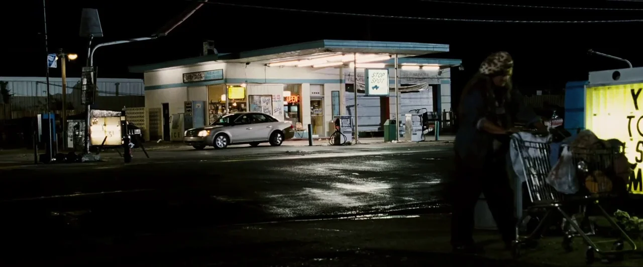 Death Sentence (2007) movie still: wide — A night-time exterior view of a weathered roadside gas station with a silver sedan parked. A lone…