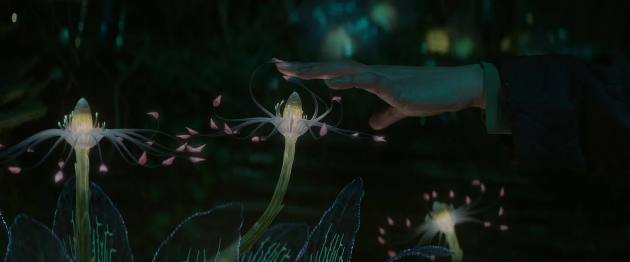 Vesper (2022) movie still: closeup — A dark environment filled with glowing bioluminescent alien flora in the deep night. A human hand reaches out…