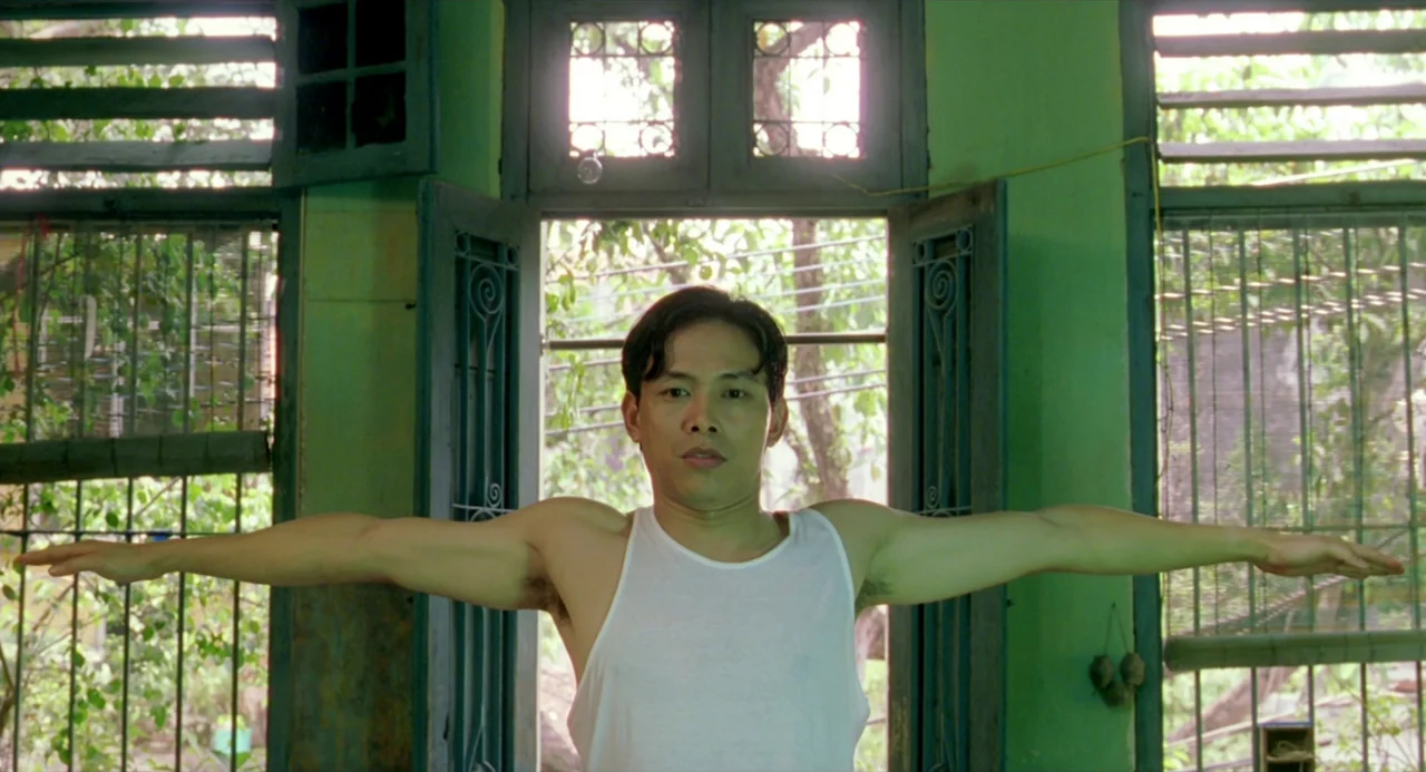 The Vertical Ray of the Sun (2000) movie still: medium — A green-walled room with large wooden-framed windows overlooks dense foliage outside. A man…