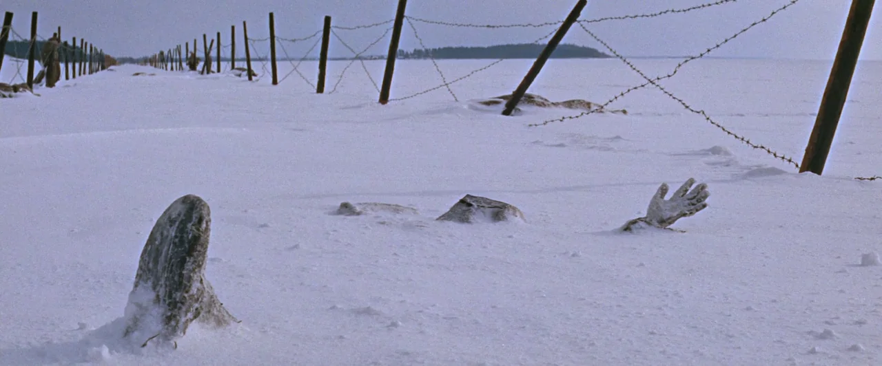Doctor Zhivago (1965) movie still: wide — A vast, flat snowy expanse is bordered by a long barbed-wire fence line. A human hand and a boot emerge…